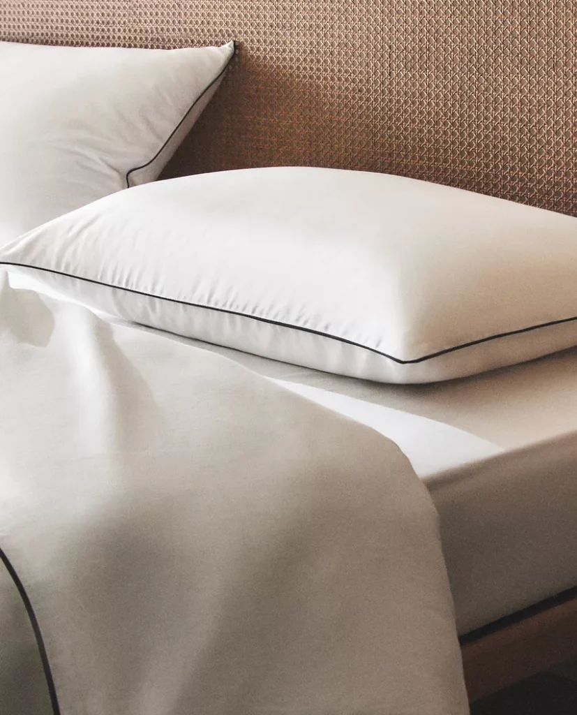 Light, airy bedroom with a fresh spring comforter, linen sheets, and soft natural light coming through sheer white curtains