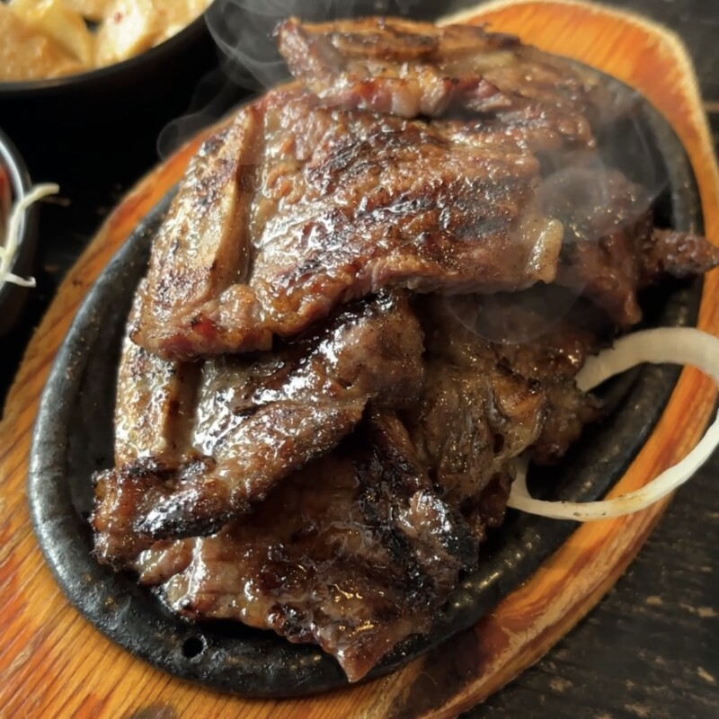 Sizzling LA Galbi (Korean BBQ short ribs) served on a hot iron plate with onions