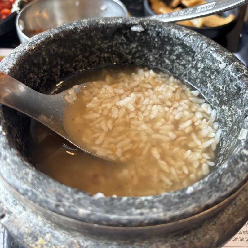 Nutty Nurungji (scorched rice soup) in a traditional Korean stone pot with a silver spoon