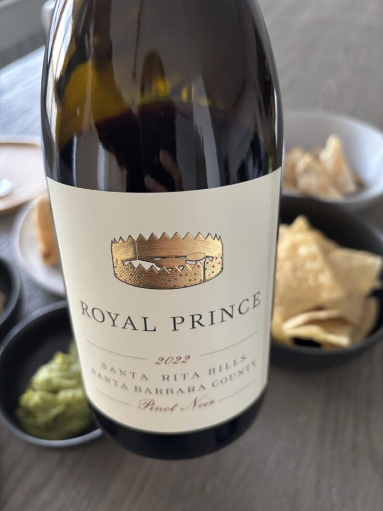 A bottle of Royal Prince Pinot Noir 2022 held against a dinner table background