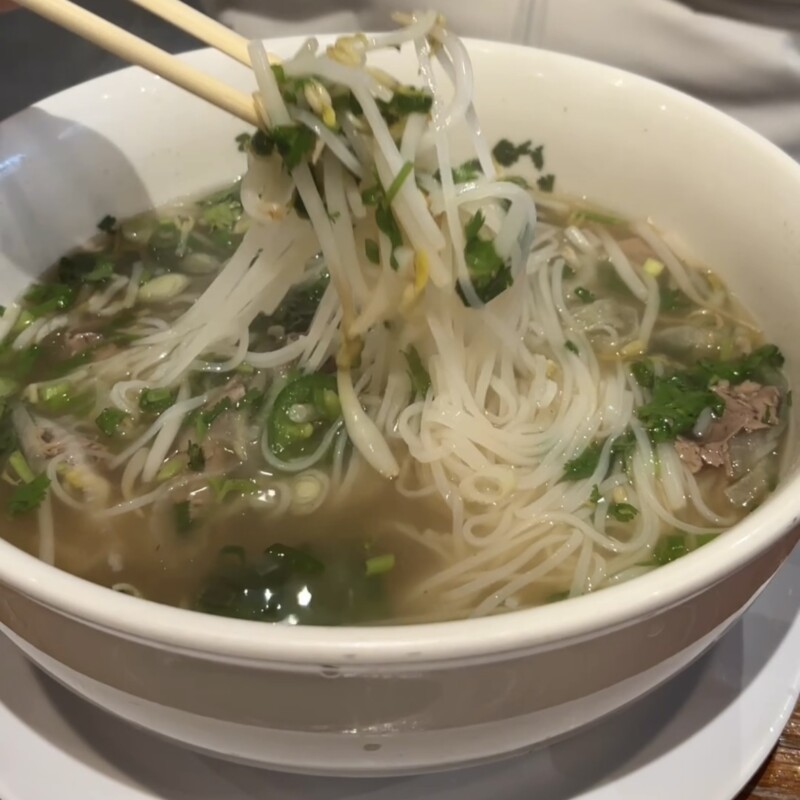 A steaming large bowl of Beef Brisket Pho at Pho Che Fort Lee with fresh herbs